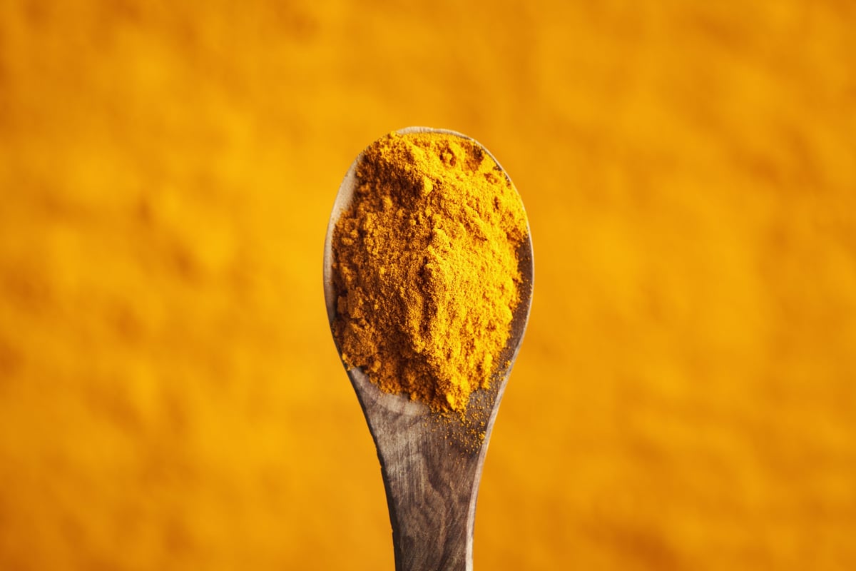 Turmeric powder on a spoon, top view with copy space