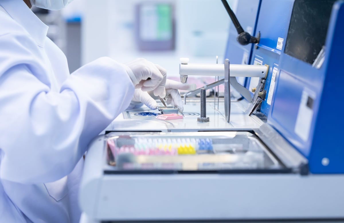 A laboratory pathologist in protective gear operates sophisticated equipment to perform scientific analysis